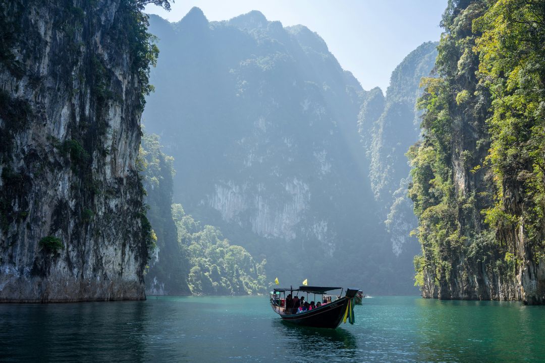 Khao Sok National Park A long tail boat floats between huge limestone plinths surround the waters of Khao Sok National Park