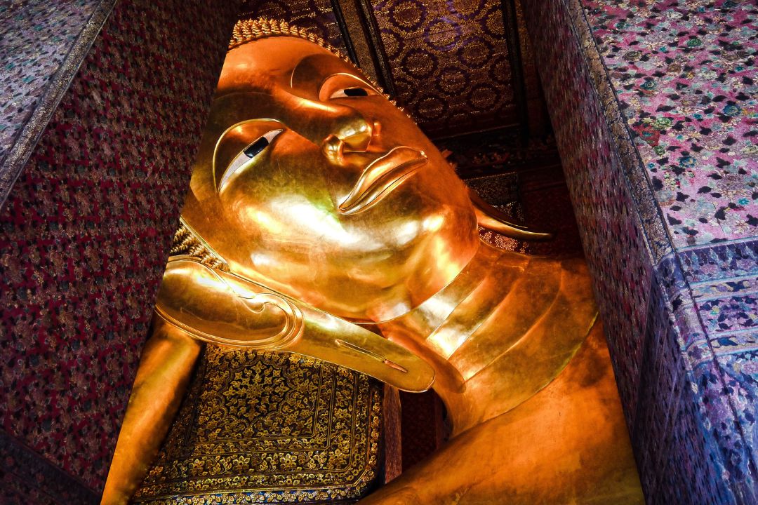 Reclining Buddha at Wat Pho, Bangkok A gigantic golden buddha head between columns at War Pho temple