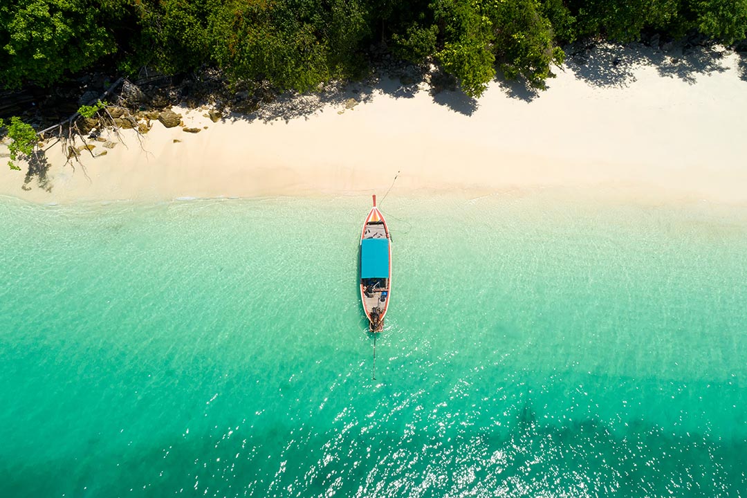 Aerial view of longtail boat on the turquoise waters and white sands of the Andaman coast, Thailand