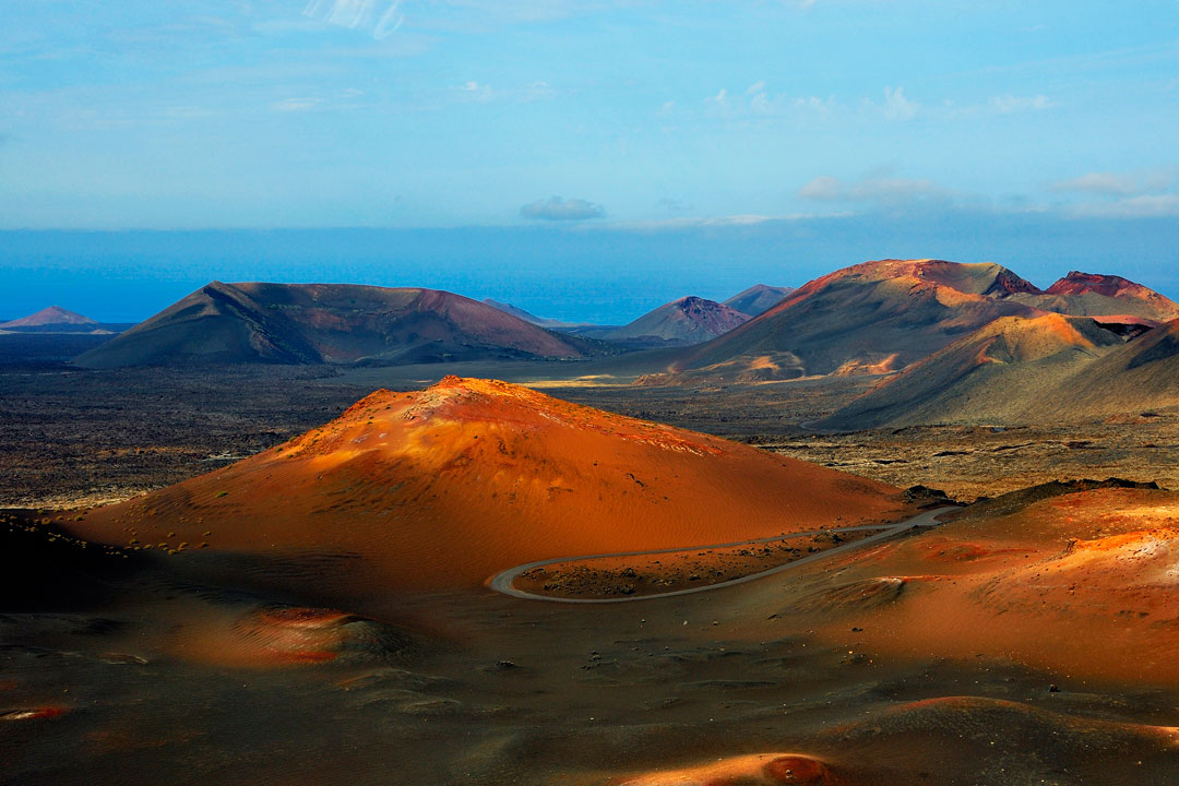 Red volcanic cones and craters leading to a blue sea