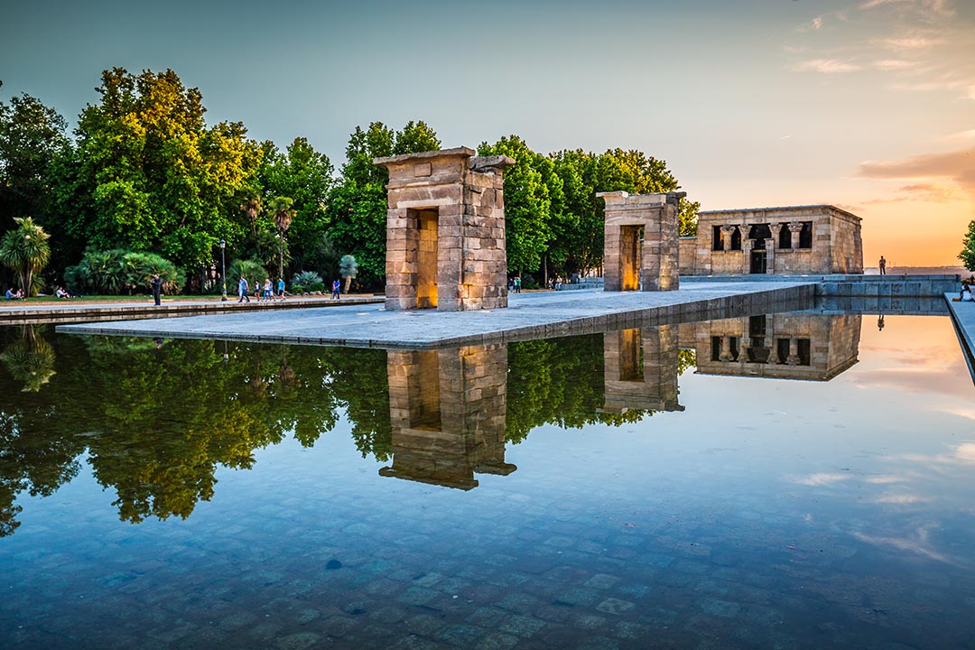 The Temple of Debod with water in front and green trees in the background