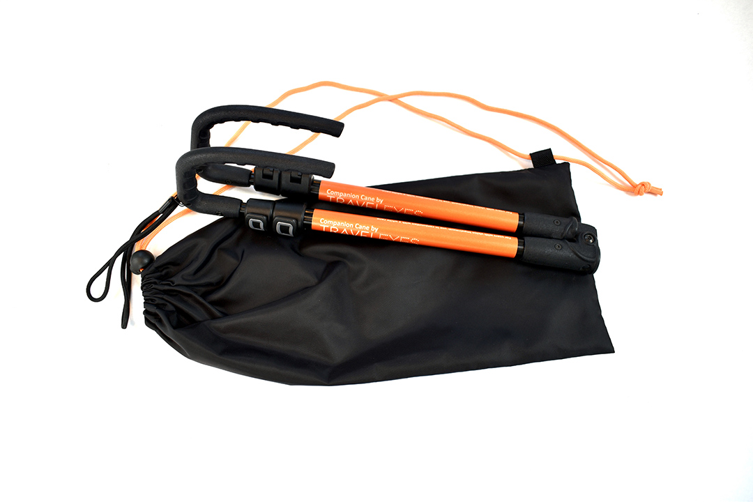 Photo description: The cane is fully collapsed with it's orange TE label on show. The cane lies on top of a black drawstring bag, with orange strings
