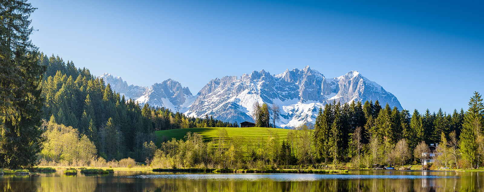 Idyllic alpine scenery, snowy mountains mirroring in a small lake.