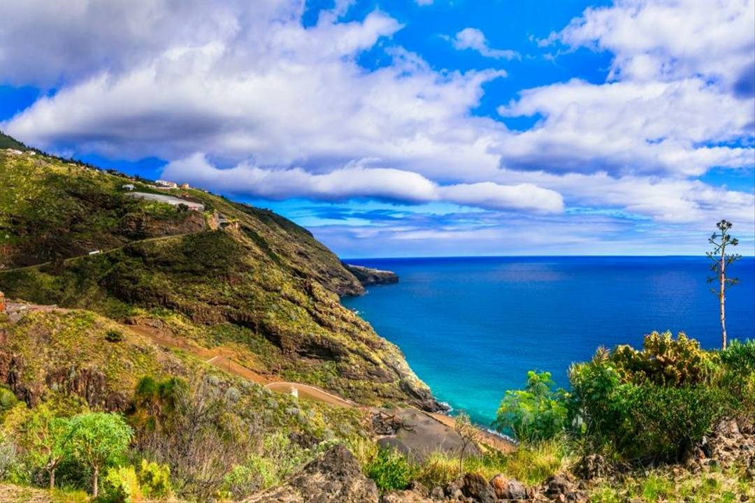 La Palma Coastline Deep blue sea, fluffy white clouds in a blue sky and rugged coastline covered in green vegetation