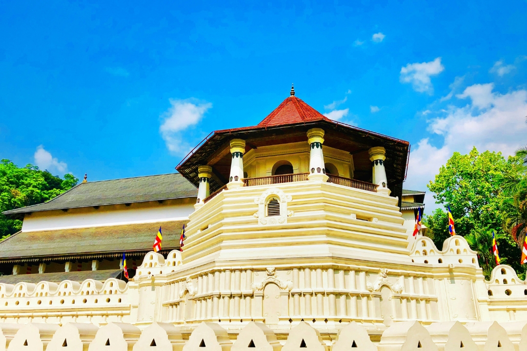 Temple of the Sacred Tooth Relic, Kandy A white walled temple with decorative carvings and a red roof in a pagoda shape