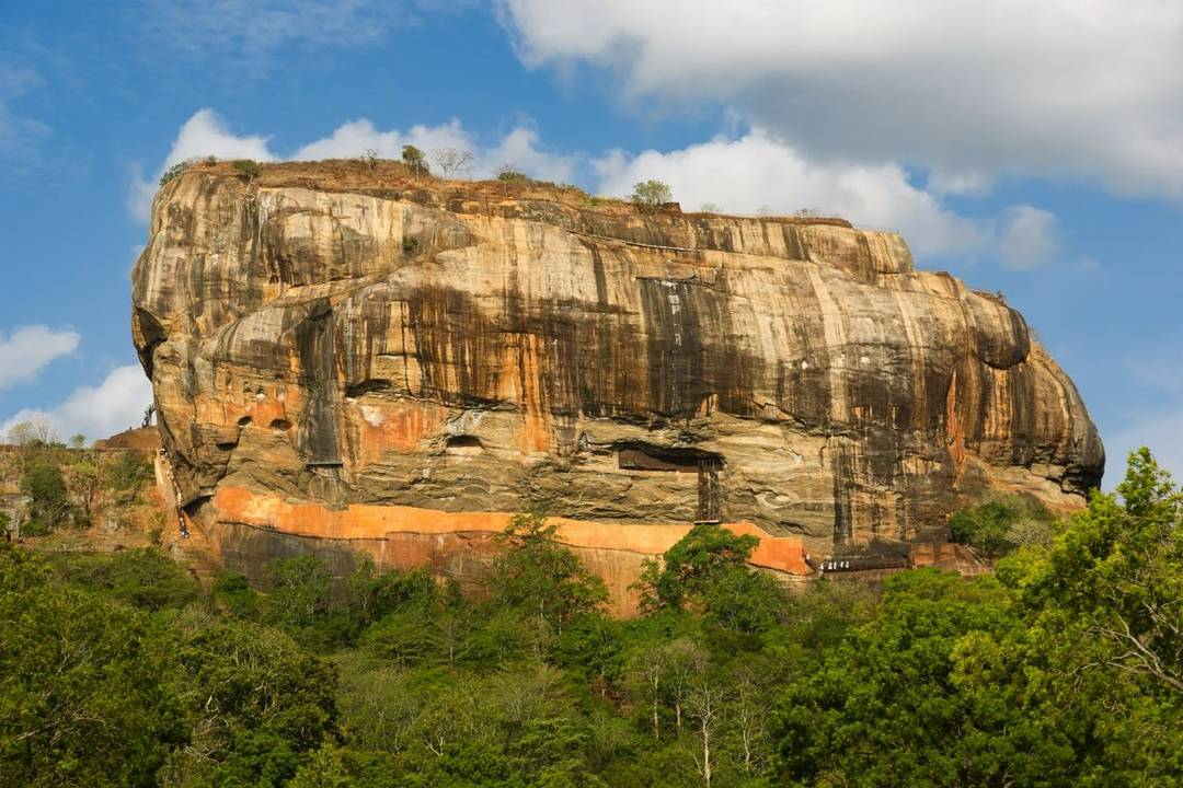 Lion Rock A large rock with streaks of sediment markings sit at the top of a high ridge with a lush forest below