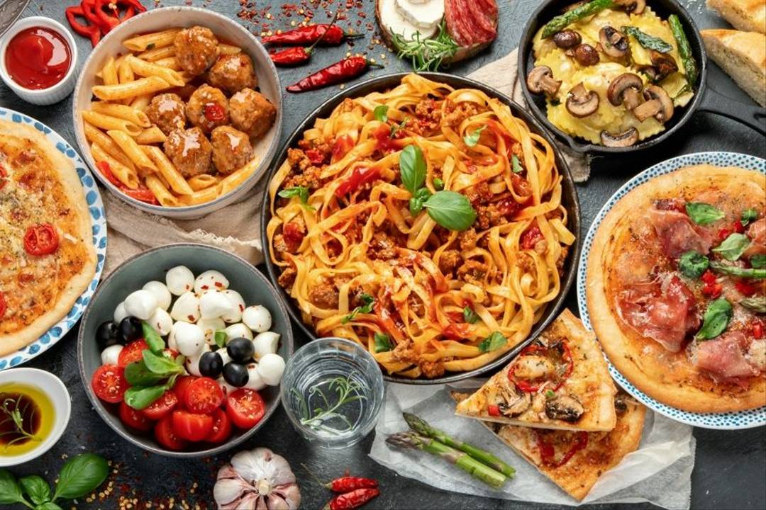 Italian food Various dishes of Italian food laid out including spaghetti bolognese, pizza, a mozzarella, tomato, black olives and basil salad, meatballs and mushroom ravioli