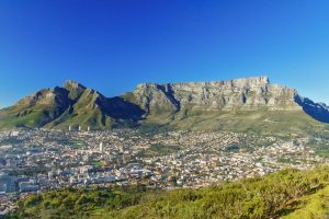Table Mountain towers over Cape Town below under a deep blue cloudless sky