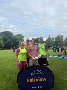 Tom and his park run crew stand in front of the parkrun sign