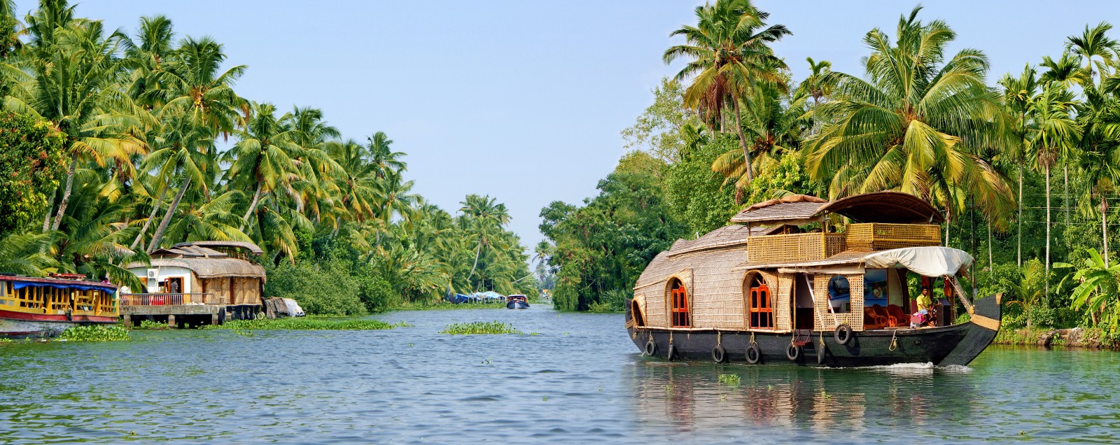 A traditional houseboat cruises gently down the backwaters of Kerala