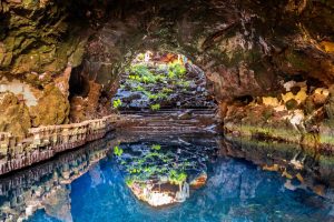 A striking volcanic cave transformed by César Manrique into an atmospheric blend of lava rock, still water, tropical plants and art