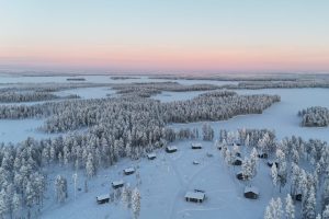 Cosy cabins nestled among snow-covered forests and frozen lakes in a peaceful winter wilderness