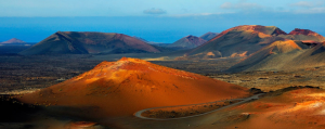 Red volcanic cones and craters leading to a blue sea