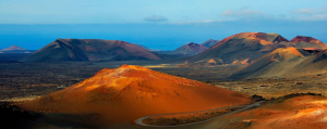 Red volcanic cones and craters leading to a blue sea