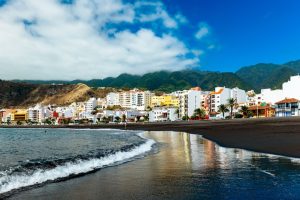 Santa Cruz de La Palma’s colourful seafront sits beside a black-sand beach, framed by dramatic green mountains and the Atlantic waves