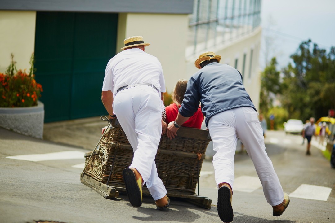 Wicker Toboggan Ride in Monte Two traditionally dressed carreiros guiding a wicker toboggan down a steep street in Monte