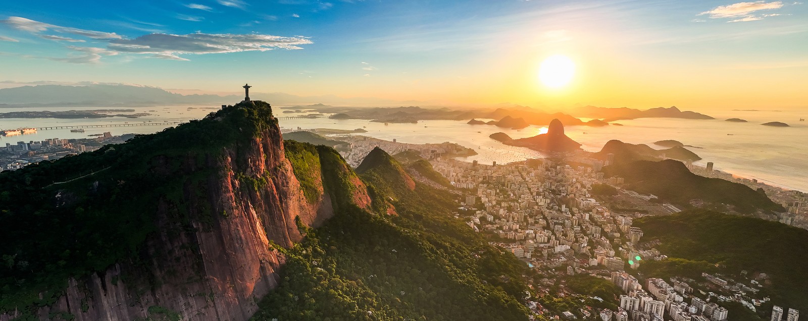 Panoramic view across Rio de Janeiro in golden sunrise light, with Christ the Redeemer on Corcovado Mountain and the city below, Brazil