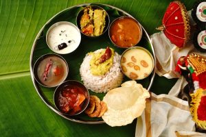 Traditional South Indian thali served on a banana leaf, with rice, curries, chutneys, yoghurt, dessert and a crisp papadum