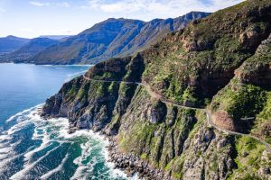 Aerial view of Chapman’s Peak Drive winding along steep green cliffs above the Atlantic Ocean
