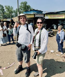 Leslie holding her camera, stands beside Luke outside of the flower market on a bright sunny day. 