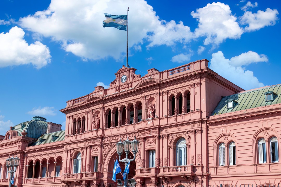 Casa Rosada, Buenos Aires, Argentina The pink façade of Casa Rosada beneath the Argentine flag and a bright blue sky in Plaza de Mayo