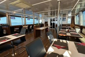 Indoor dining area aboard Seagull, with laid tables and large windows overlooking the Adriatic Sea