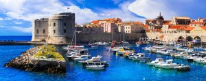 Dubrovnik Old Port with boats in the harbour, historic city walls and St John Fortress overlooking the Adriatic Sea, Croatia