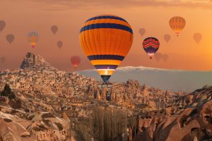 Hot-air balloons floating above Cappadocia’s rocky valleys and cave settlements at sunrise, Cappadocia