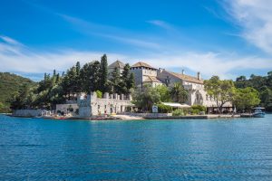 Benedictine monastery on St Mary’s Island surrounded by the calm blue waters and wooded landscape of Mljet National Park, Croatia