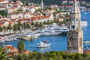 View over Hvar Town with its historic bell tower, palm-lined waterfront and boats moored in the harbour, Croatia