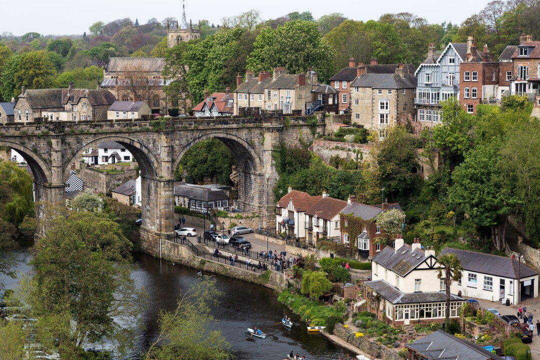 Historic stone railway viaduct spanning the River Nidd, with riverside houses and boats in Knaresborough