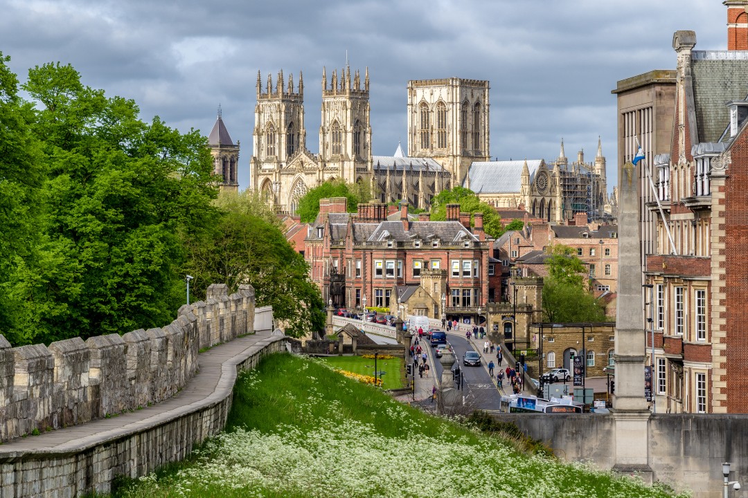 York Minster The tall gothic towers of York cathedral dominate the skyline with streets, green lawns and the city walls in the foreground