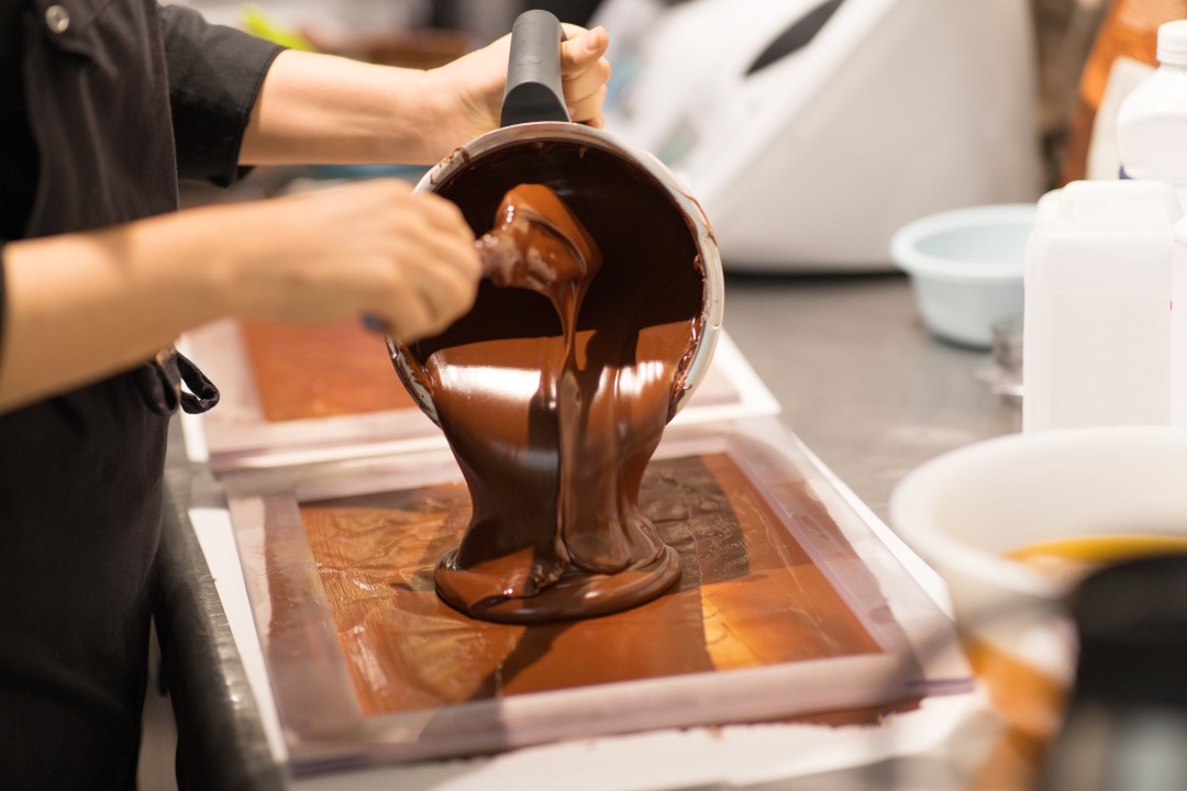 Traditional Chocolate Making Melted chocolate being poured from a bowl into a rectangular mould during a chocolate-making demonstration